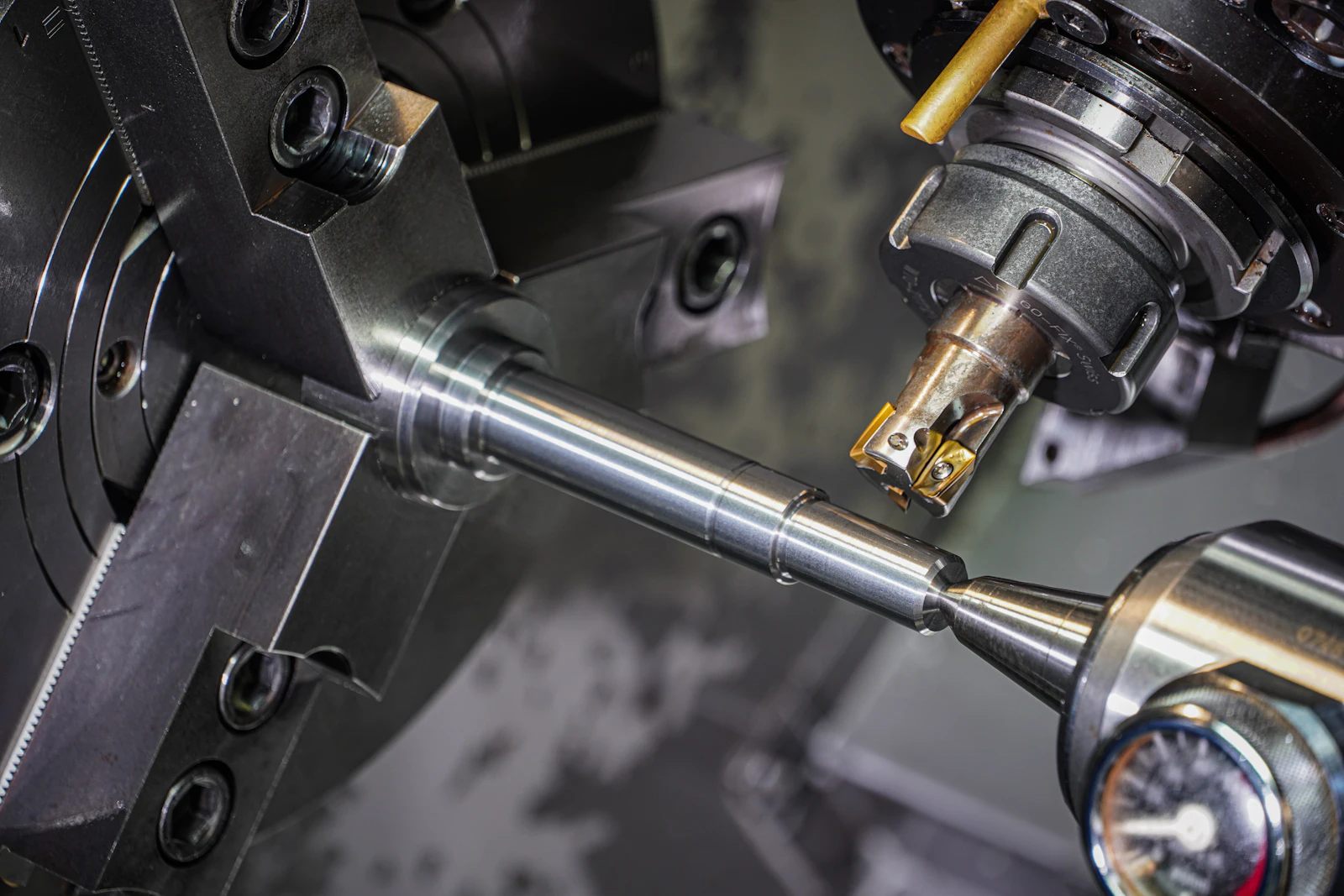 Metal bar held in a lathe chuck being turned by a cutting tool