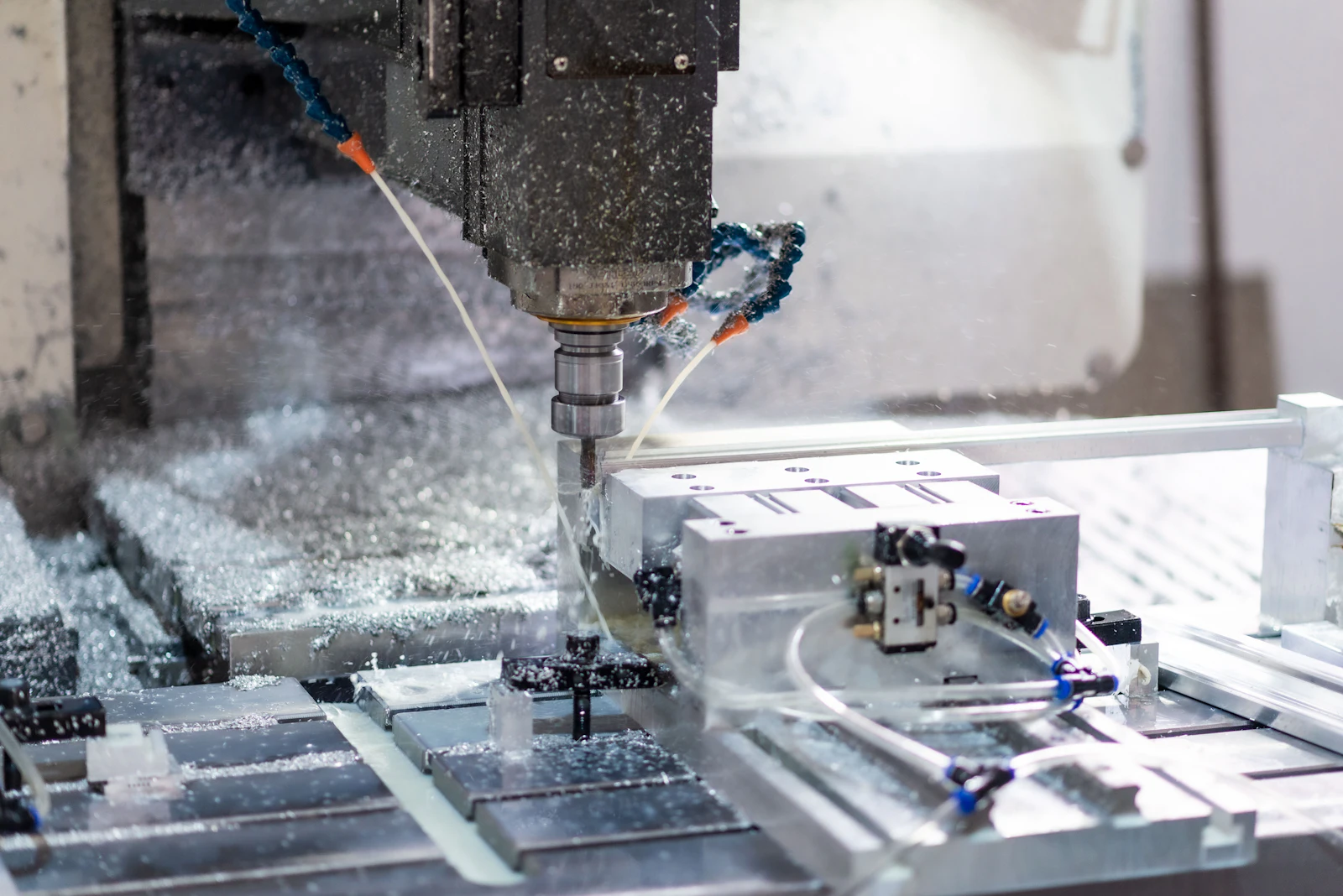 CNC milling machine cutting an aluminum part with coolant spray